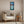 Load image into Gallery viewer, Daisies by Adam Young framed in black on a beige living room wall above a linen armchair and wooden side table

