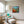 Load image into Gallery viewer, Patch of Poppies by Adam Young framed beside an armchair and reading lamp
